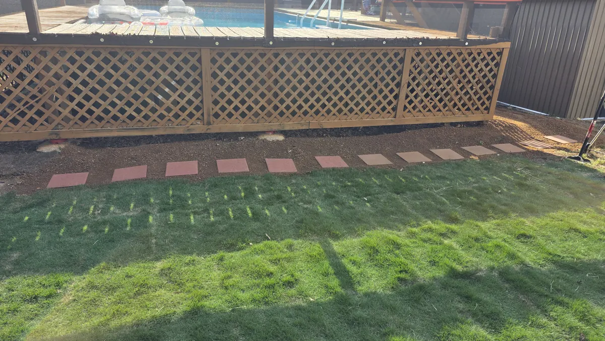 Finished French drain path with red stepping stones and decomposed granite in front of a backyard deck